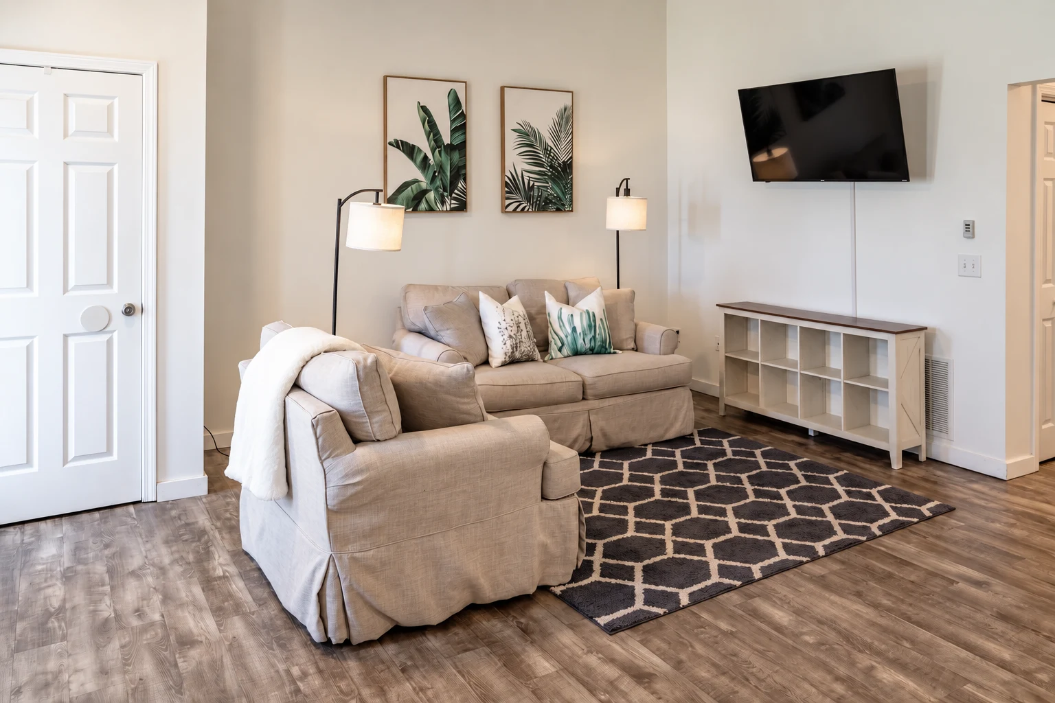 6319 living room with two neutral upholstered seats, a patterned rug and wall-mounted TV