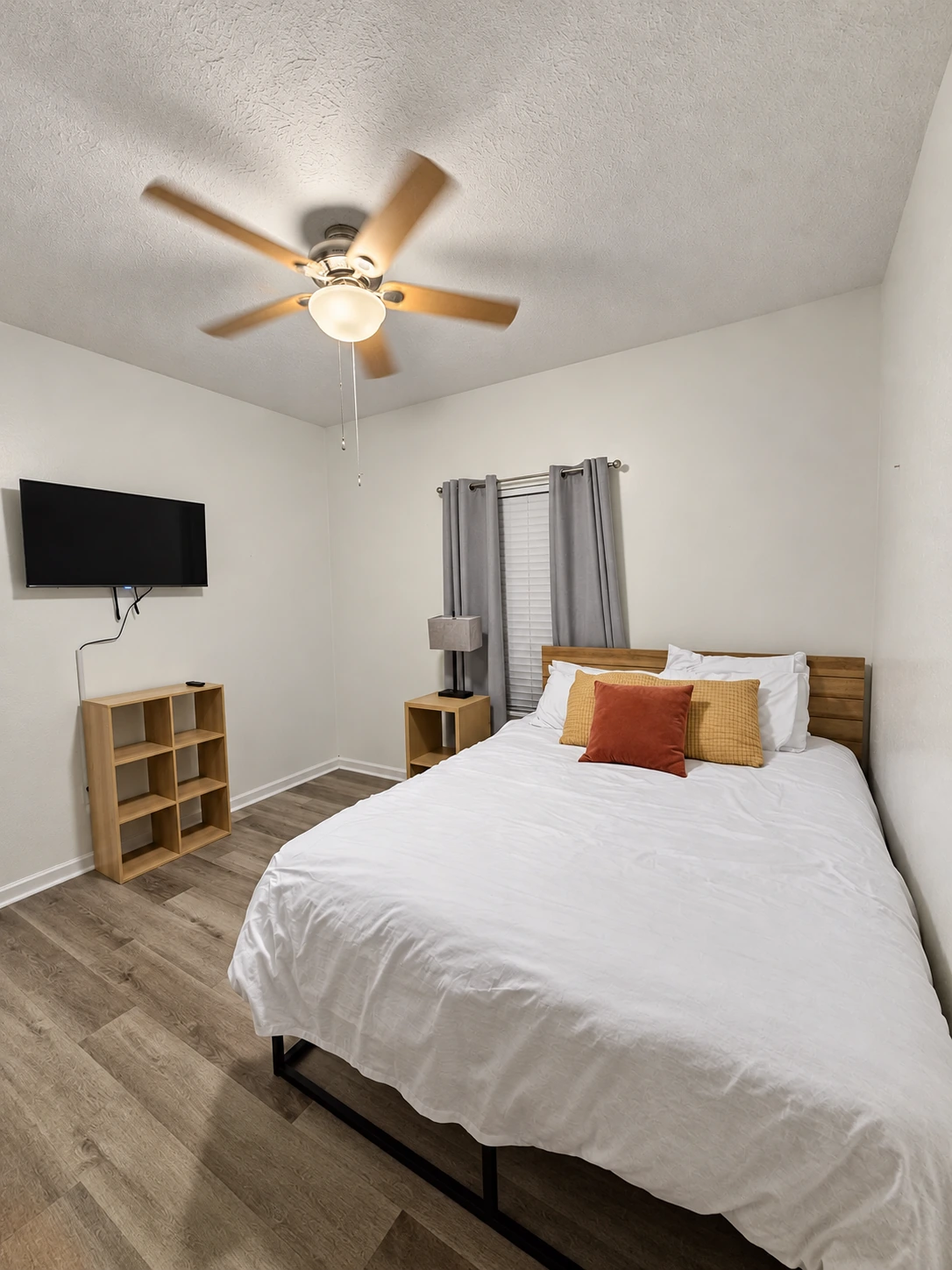 Queen bed in a bright bedroom with ceiling fan and Roku TV